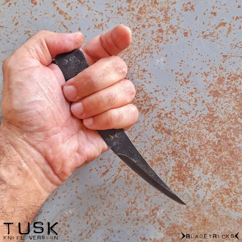 Bladetricks Tusk pikal knife held in a closed fist, showing the curved bellied edge running to a fine point.