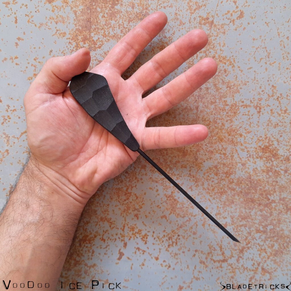 Bladetricks Voodoo ice pick held in an open palm, a one-piece black steel tool with a faceted teardrop handle tapering to a long spike with no cutting edge.