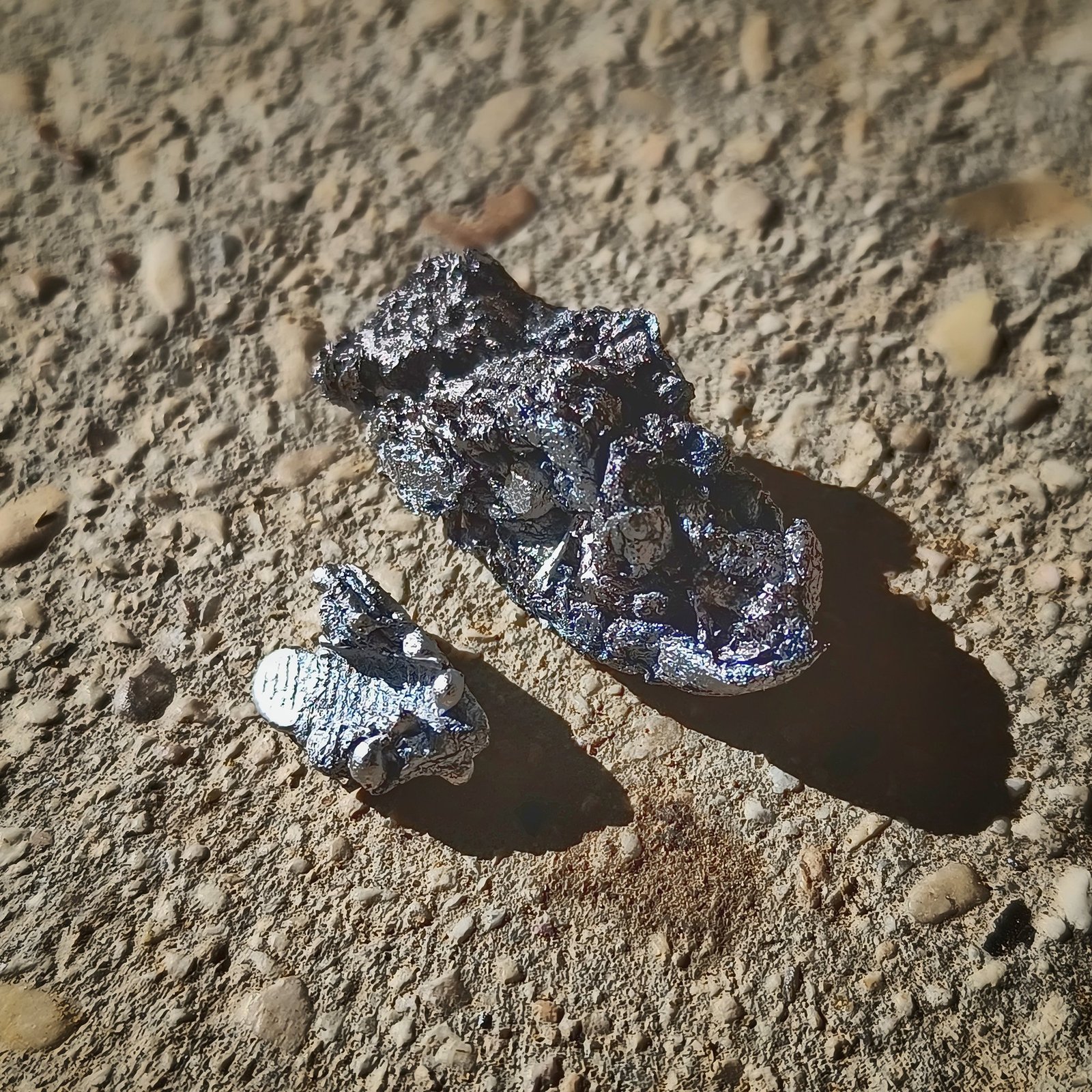 Two compressed aluminum foil balls from a kiln calibration test, one partially melted, one fully melted showing plier marks and round extruded beads of aluminum