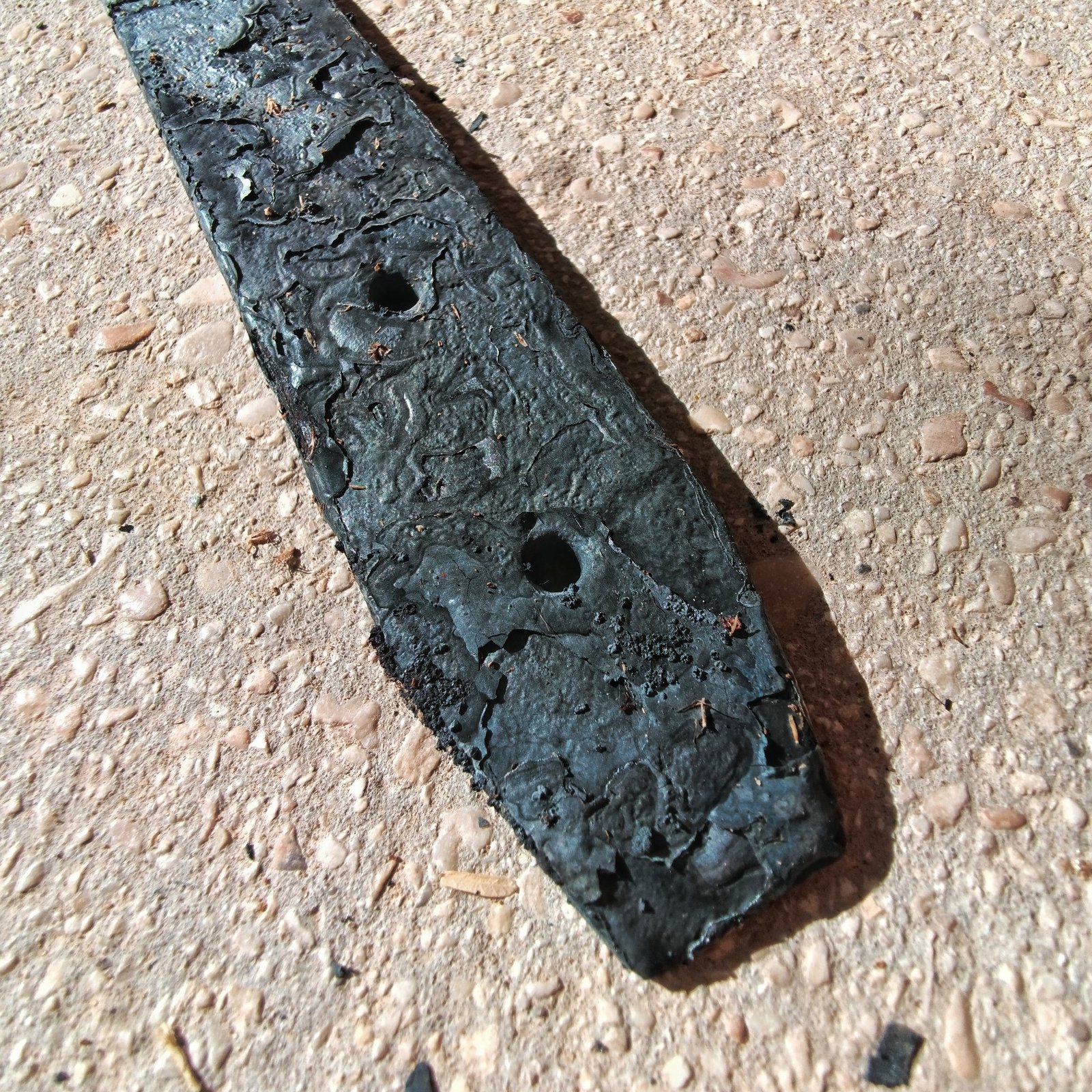 Strip of spring steel corroded and pitted by molten salt spilled inside a heat treating kiln